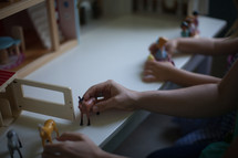 a mother playing doll house with her daughters 
