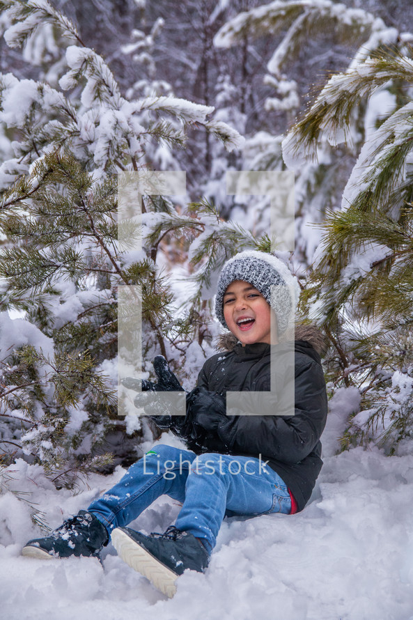 Boy laughing while playing in the snow