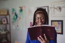 Smiling woman holding and reading a Bible.