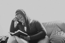 Woman sitting on the sofa reading the Bible.