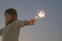 a young woman holding a sparkler 