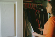 A young woman looking in the closet at clothing