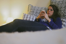 a teen girl texting in her bedroom 