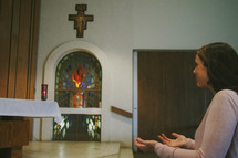 A young woman kneeling and praying in a Catholic church
