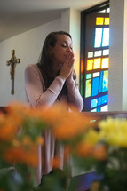 A  joyful young woman kneeling in prayer at a Catholic church