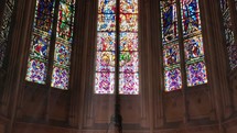 Sunlight passing through stained glass windows depicting religious scenes