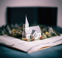 Miniature model of christian church and book on blue background.