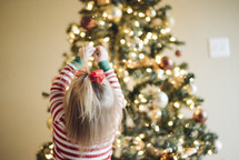 toddler girl decorating a Christmas tree