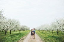 happy couple standing in an orchard 