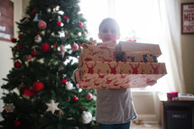 a child holding a stack of Christmas presents 