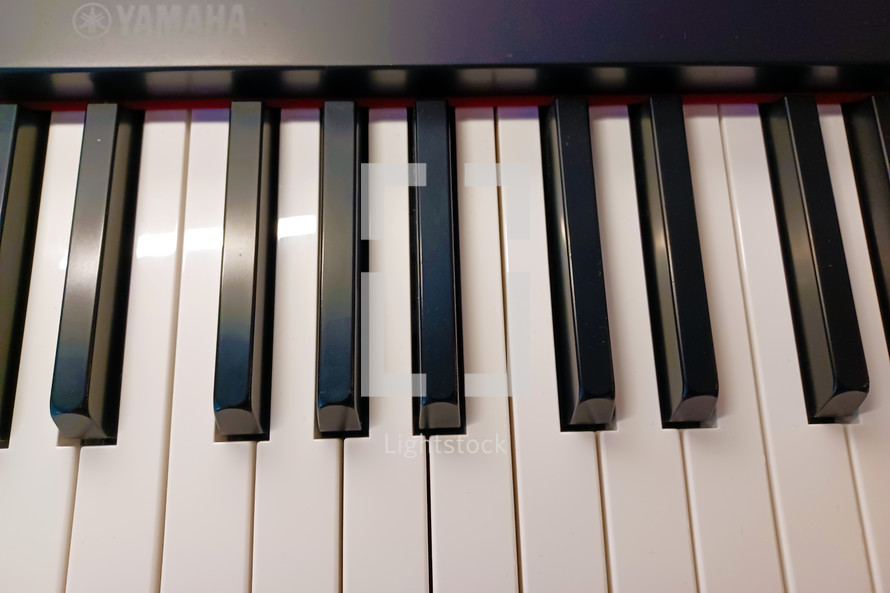 An up close photograph of an electric piano keyboard showing the white keys on the keyboard