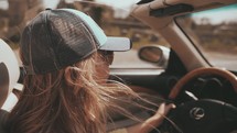 a woman's hair blowing in the breeze as she drives a convertible 