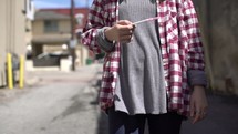 teen pregnancy, pregnant teen walking outdoors holding a pregnancy test 