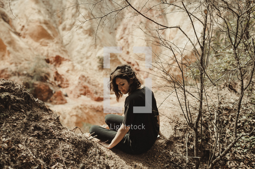 a woman sitting on a rock outdoors 