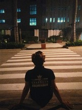a young man sitting on a crosswalk at night 