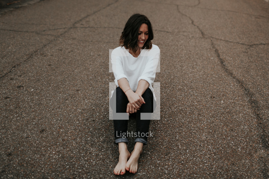 a woman sitting in the middle of a road 