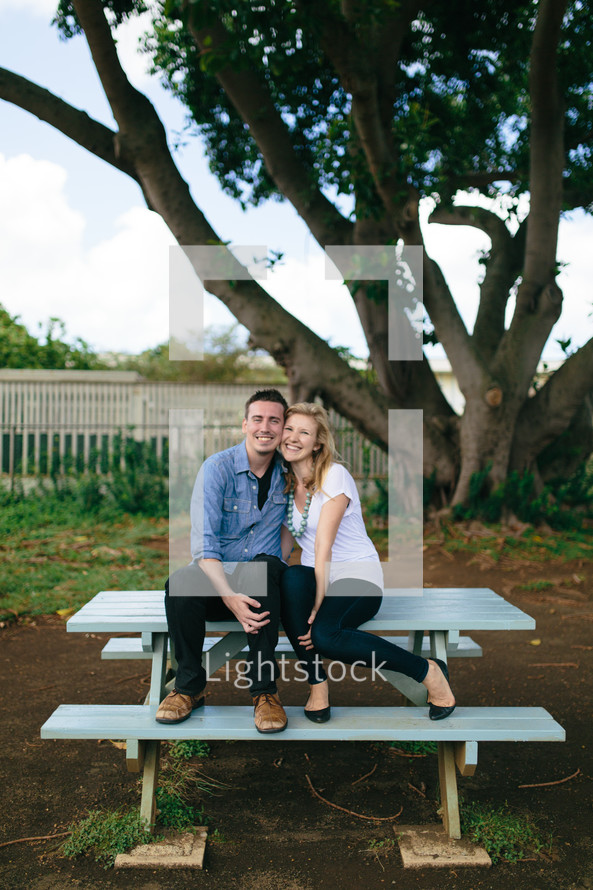 couple snuggling on a picnic table 