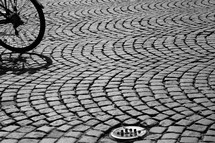 Bicycle wheel on arched cobblestone street.