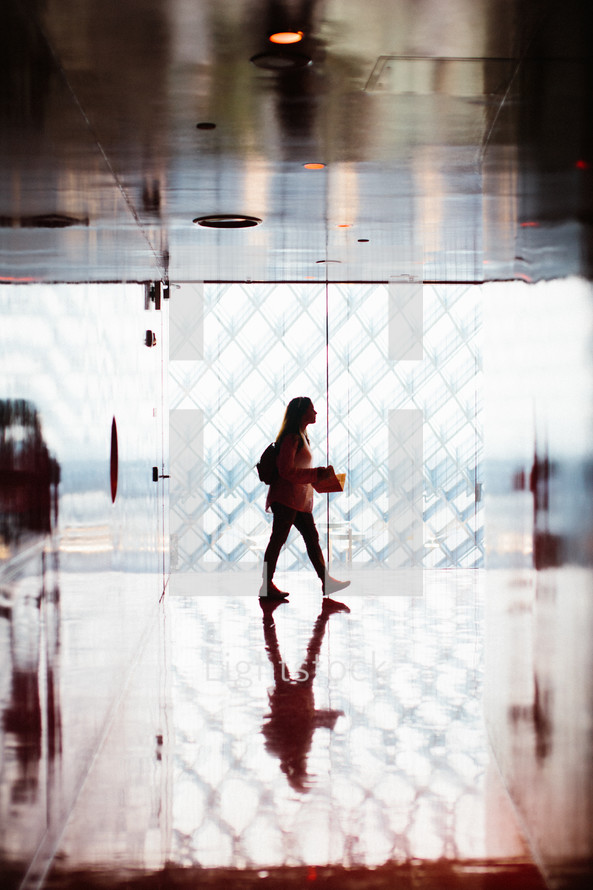 a woman with a backpack walking down a hallway 