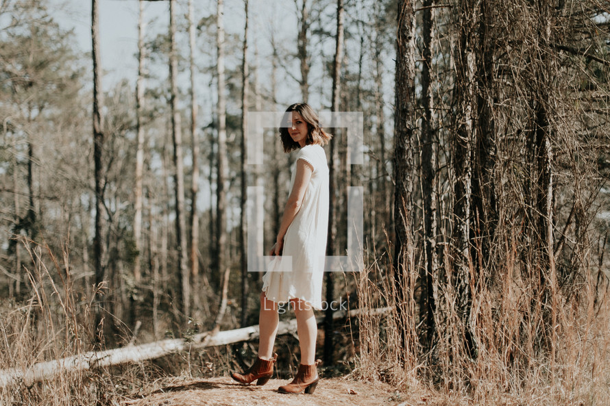 a woman in a dress standing alone in the woods 