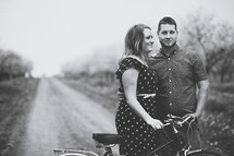 happy couple standing in an orchard with a bicycle 