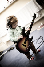 toddler boy with headphones and a guitar