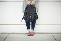 girl standing next to a book bag 
