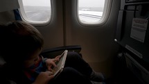 Boy using tablet PC in plane going to take off
