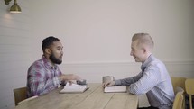 two men having a conversation over coffee and discussing scripture 