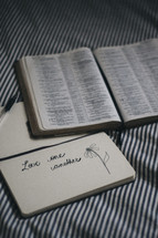 Love one another written in the pages of a journal and an open Bible 