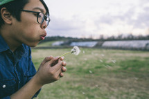 Girl blowing a dandelion flower in a field