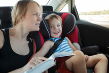 Mother reading a book to son in the car