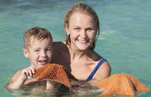 Mother and son in sea holding starfish