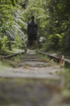 a man standing on railroad tracks in a jungle 