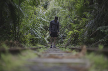 man standing on train tracks in a jungle 
