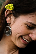 A woman's ear with an earring and flower behind her ear