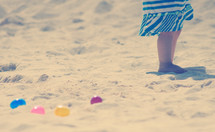 Child's legs on the beach with Easter eggs.