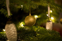 gold Christmas ornaments hanging on a Christmas tree