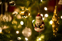 glass Santa ornament hanging on a Christmas tree