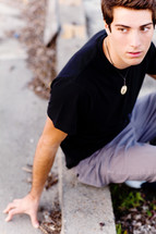 teen young man  sitting on a curb model fashion