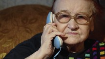 Elderly woman in glasses taking a call