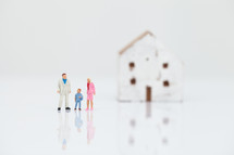 miniature figurines of a family in front of a house 