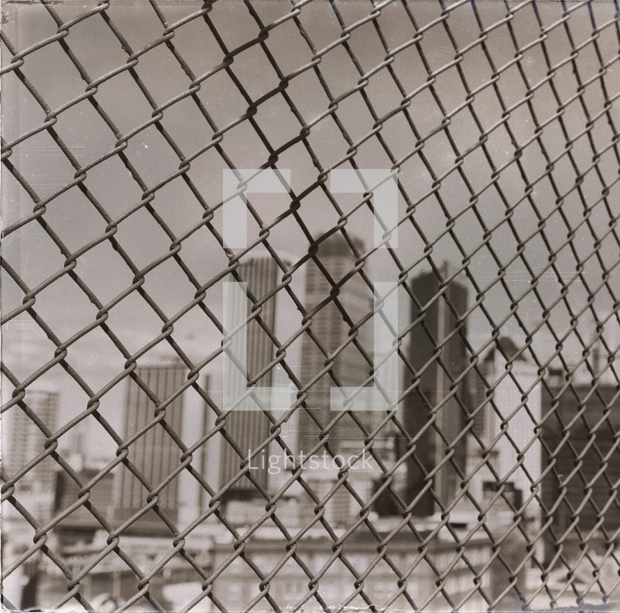 city buildings behind a chain link fence 