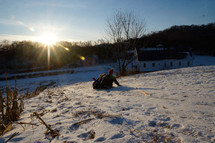 kids sledding down a hill at sunset 