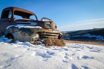 rusted abandoned vehicle in snow 