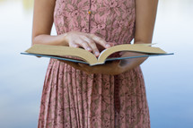 torso of a woman in a pink dress reading a book 