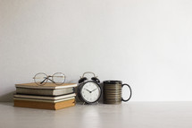 Reading concept with reading glasses, clock and coffee cups with light. 