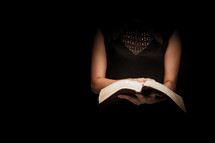 a torso of a woman reading a Bible 