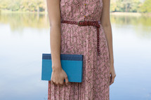torso of a woman in a pink dress holding a Bible 