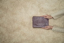 a woman holding a Bible over a rug 